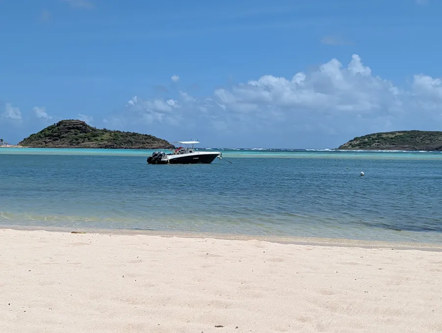 The sheltered cove at Grand Cul de Sac, St. Barths — shallow turquoise water, beach chairs set out, a single boat moored in the inlet