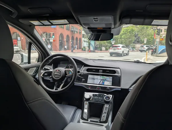 Inside a driverless Waymo, empty driver seat and dashboard screen, stopped at a San Francisco intersection